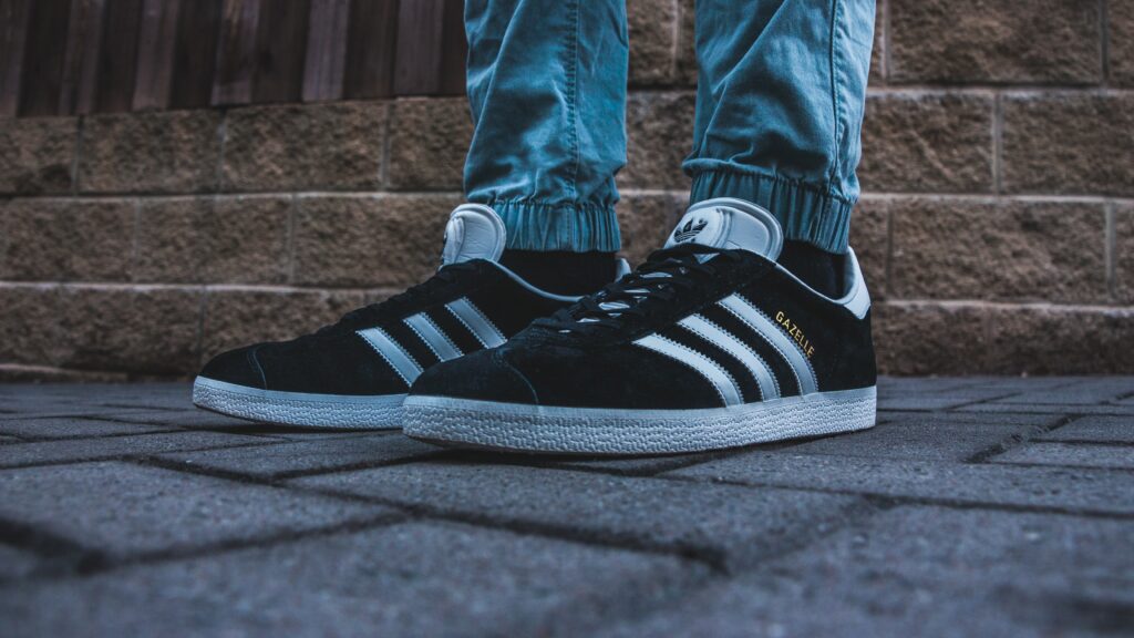 Person wearing a pair of black and white Adidas Gazelle